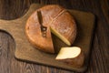 Cheese wheel and slice on a cutting board over a wooden table on Royalty Free Stock Photo