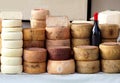 Cheese wheels of Pecorino and Sardinian ricotta in different stacks on a shelf of an outdoor market.