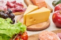 Cheese on wooden cutting board near assorted meat, fish fruits and vegetables. Royalty Free Stock Photo