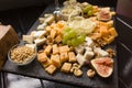 Cheeseboard or assorted of cheese. Abundance of gourmet cheeses with fig, grapes and nuts on black wooden plank