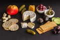 Cheeseboard with camembert, cheddar, crackers, olives, figs, dates and pickles on black texture Royalty Free Stock Photo