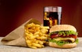 Cheeseburger with drink of cola, french fries on red spotligh