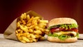 Cheeseburger, french fries on red background on wooden plank