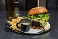 Cheeseburger with vegetables, garlic sauce and french fries on a wooden table