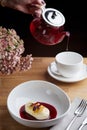 Cheesecake with berry sauce and pouring red tea on background. breakfast morning table with flowers. cottage cheese pancakes