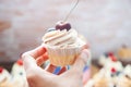 Cheesecake cupcake with cream cheese frosting and fresh cherry on top, wooden background Royalty Free Stock Photo