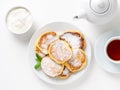 Cheesecake, curd fritters. Cottage cheese pancakes with powdered sugar. Sweet fried cheese pancakes on white plate on white