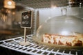 cheesecake displayed on the grill of a fridge with an indicative sign in Spanish