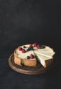Cheesecake with fresh berries on cutting board on dark background