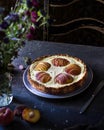 Cheesecake with peaches on a dark table with a bouquet of flowers.