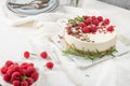 Cheesecake with raspberries, chocolate, hazelnuts and rosemary leaves on kitchen coutertop