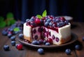 A cheesecake with a topping of blueberries and berry glaze, on a rustic plate with scattered berries on a wooden table over dark