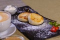 Cheesecakes with strawberries. Two fried curds on a black tray. Close-up. Royalty Free Stock Photo