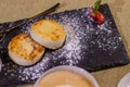 Cheesecakes with strawberries. Two fried curds on a black tray. Close-up. Royalty Free Stock Photo