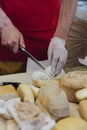 Cheesemaker cuts cheese. Pieces of cheese on a wooden board with cook hands and a knife. Cutting cheese, slicing cheese. close-up Royalty Free Stock Photo