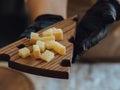 Cheesemaker cuts cheese. Pieces of cheese on a wooden board with cook hands and a knife. Cutting cheese, slicing cheese. close-up Royalty Free Stock Photo