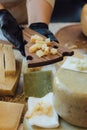 Cheesemaker cuts cheese. Pieces of cheese on a wooden board with cook hands and a knife. Cutting cheese, slicing cheese. close-up Royalty Free Stock Photo