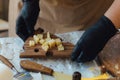 Cheesemaker cuts cheese. Pieces of cheese on a wooden board with cook hands and a knife. Cutting cheese, slicing cheese. close-up Royalty Free Stock Photo