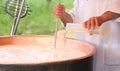 Cheesemaker pours milk rennet in copper pot for making cheese Royalty Free Stock Photo