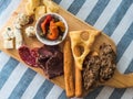 Cheeses, sausages, bruschettas, olives and capers on a wooden board on a table with a linen striped tablecloth Royalty Free Stock Photo