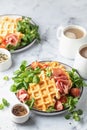 Cheesy belgian waffles served with ham, tomatoes and lettuce corn on white marble background . Savory waffles. Healthy