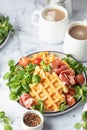 Cheesy belgian waffles served with ham, tomatoes and lettuce corn on white marble background . Savory waffles. Healthy
