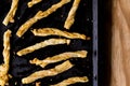 Cheesy cheese pastry straws with sesame seeds and bits of chili in oven pan - top view photo