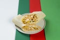 Cheesy shawarma roll served on gray plate, colorful red, white, green abstract background Royalty Free Stock Photo