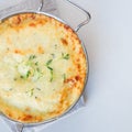 Cheesy scalloped potatoes or potato gratin in a baking dish, holiday theme, square format, top view, copy space