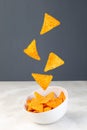 Cheesy tortilla chips or nacho levitate above the bowl, vertical