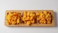 Cheetos is a crunchy corn puff snack. Bright orange cheese puffs in a wooden board