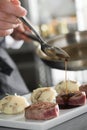 Chef add sause to a beef steaks, grey backgroung Royalty Free Stock Photo