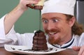 Chef added chocolate sauce at piece of cake Royalty Free Stock Photo