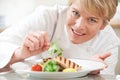 Chef Adding Garnish To Meal In Restaurant Kitchen