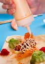 Chef adding sauce to a plate of salmon tartare