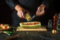 The chef adds cheese to stuffed squash on the kitchen table. The concept of cooking national stuffed zucchini or marrow for lunch Royalty Free Stock Photo