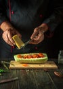 The chef adds cheese to stuffed squash on the kitchen table. The concept of cooking national stuffed zucchini or marrow for lunch