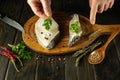 The chef adds green parsley to Anarhichas fatty fish steaks. The process of preparing a fish dish with spices by the hands of a Royalty Free Stock Photo