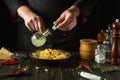 The chef adds olive oil to a bowl of pasta on the kitchen table. Low key concept of preparing a delicious breakfast in a public Royalty Free Stock Photo