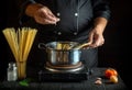 The chef adds salt to Stock pot of boiling water. Cooking Italian spaghetti in the restaurant kitchen Royalty Free Stock Photo