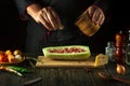 The chef adds salt to the zucchini on the kitchen table. The concept of cooking national stuffed zucchini or mahshi for dinner