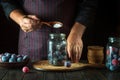 The chef adds sugar to the plums in the jar. Preparing or preserving sweet compote or fruit drink in a restaurant kitchen