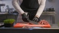 Chef in apron cuts pieces of meat at cutting board Royalty Free Stock Photo