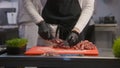 Chef in apron cuts pieces of meat at cutting board Royalty Free Stock Photo