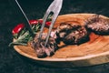 Chef in apron with meat fork and knife slicing gourmet grilled steaks with rosemary and chili pepper on wooden board Royalty Free Stock Photo