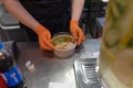 Chef in an Asian restaurant packs the wok into a container. Restaurant worker in the kitchen wearing gloves and an apron