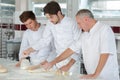 Chef and assistants at work with unbaked loaf bread Royalty Free Stock Photo