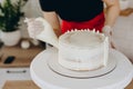 Chef or baker decorating cake with white whipped cream. Royalty Free Stock Photo