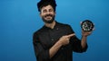 Chef with beard pointing at clock against blue background, emphasizing time management in a culinary setting Royalty Free Stock Photo