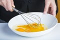 Chef beating eggs in a bowl witha a manual mixer